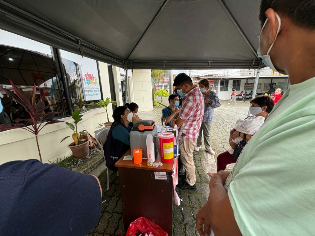 Ciudadanos esperan su turno en la fila por la vacunación contra la tosferina en el subcentro Los Rosales, en Santo Domingo, en medio de medidas de prevención.