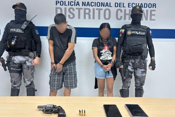 La pareja detenida junto al arma de fuego que se les encontró después de una persecución.