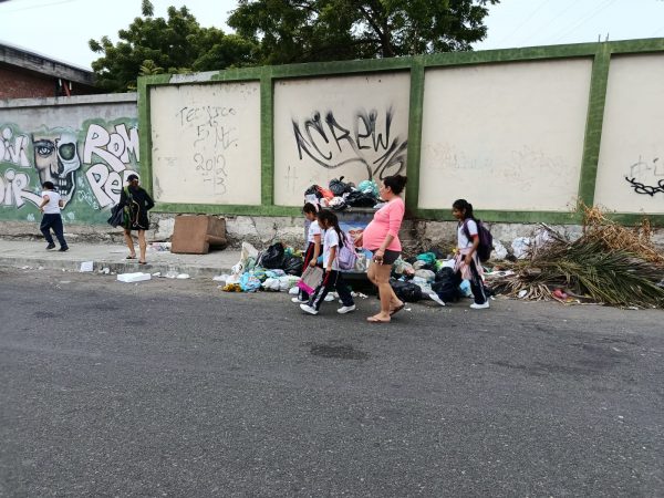 Madres de familia y alumnos esquivan la basura al entrar y salir de sus planteles educativos. Malestar se presenta en la calle 18A.