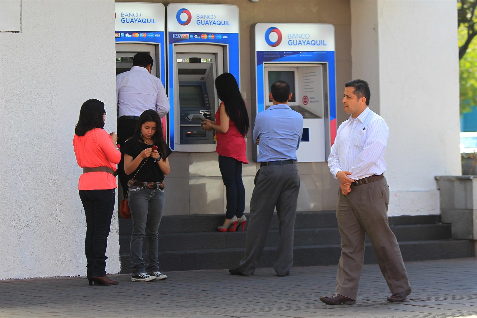 Ciudadanos ecuatorianos hacen fila en un cajero automático en Quito