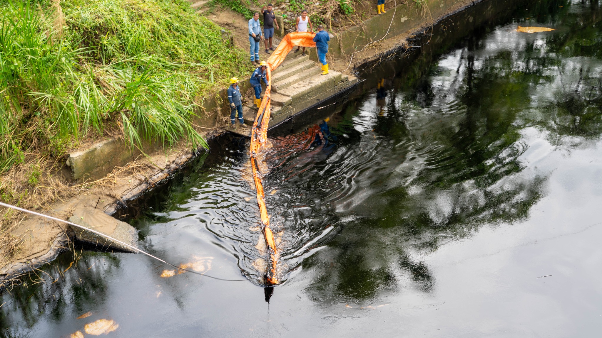 Con mangueras buscan succionar el petróleo derramado en el río Esmeraldas. Foto: Cuerpo de Bomberos de Esmeraldas.