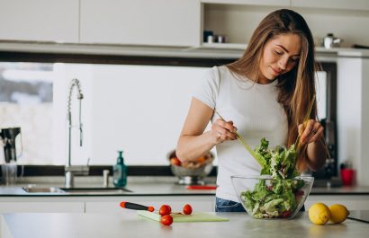 Young woman making salad at the kitchen