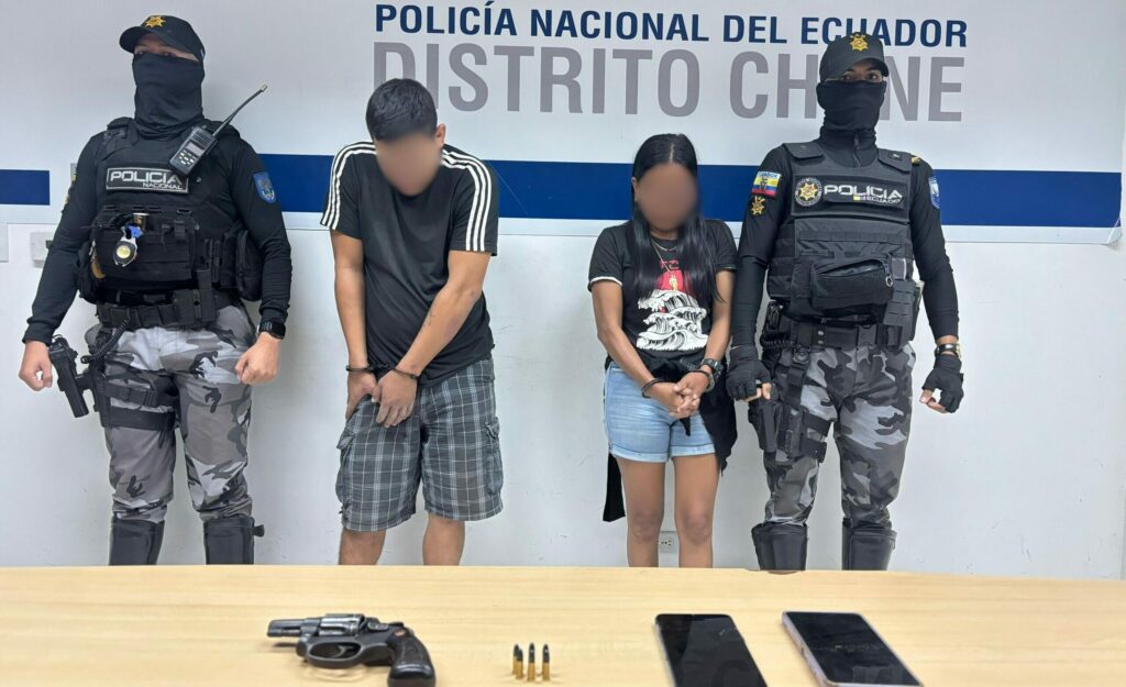 La pareja detenida junto al arma de fuego que se les encontró después de una persecución.