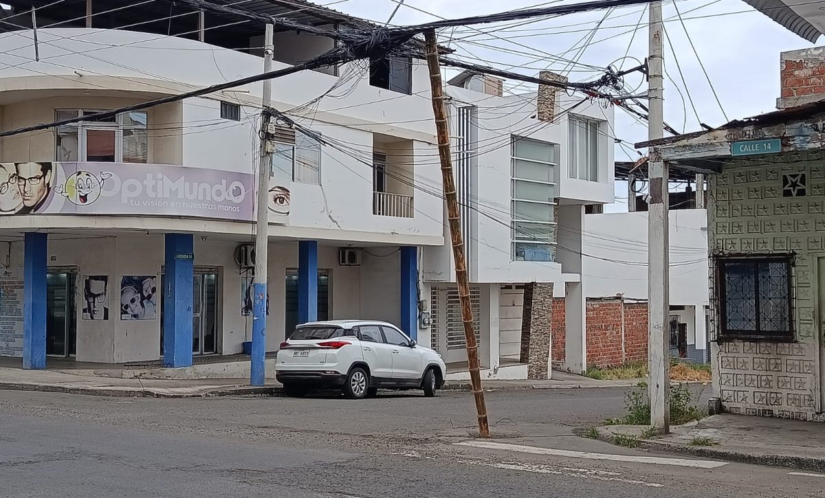 Una caña improvisada sostiene cables de telecomunicaciones en la calle 14 y avenida 14, en Manta.