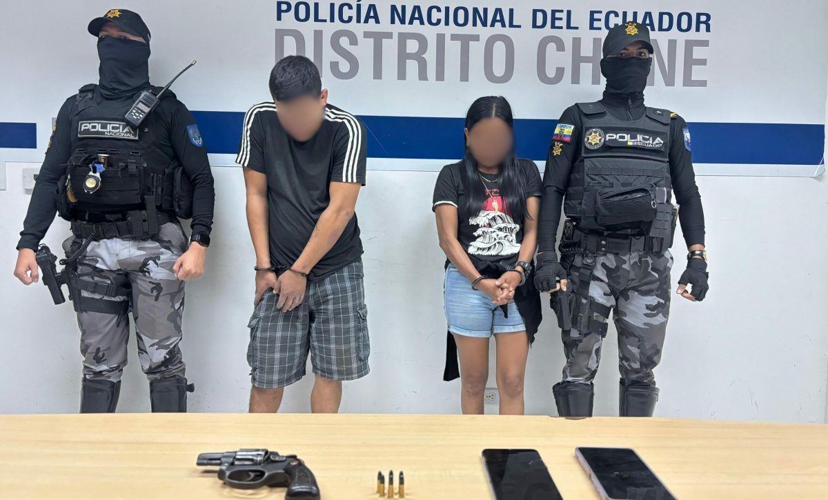 La pareja detenida junto al arma de fuego que se les encontró después de una persecución.
