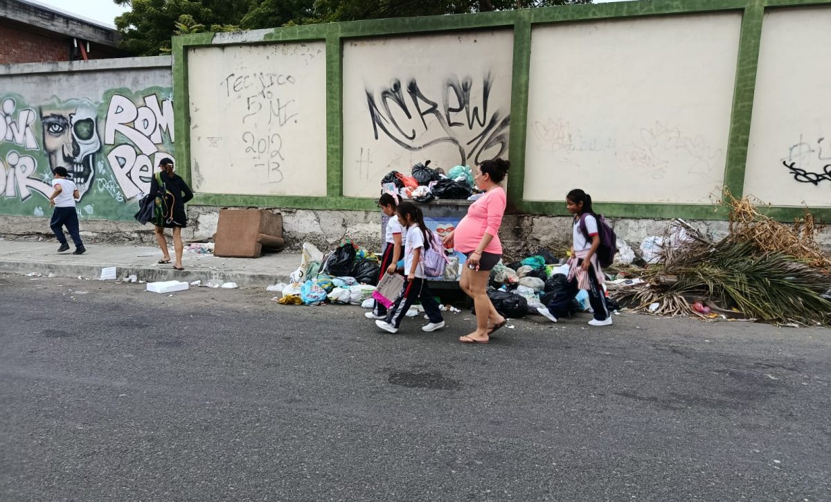 Madres de familia y alumnos esquivan la basura al entrar y salir de sus planteles educativos. Malestar se presenta en la calle 18A.