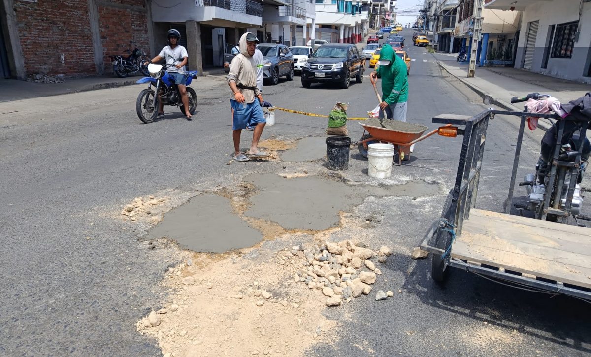 Carlos Hernández junto a Josué Mieles y Javier Basurto mientras tapaban los baches en la calle 14 y avenida 7 en el centro de Manta.