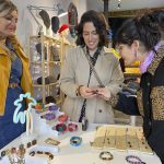 Milena Zavala (c) muestra algunas de las piezas artesanales de tagua que vende en Madrid