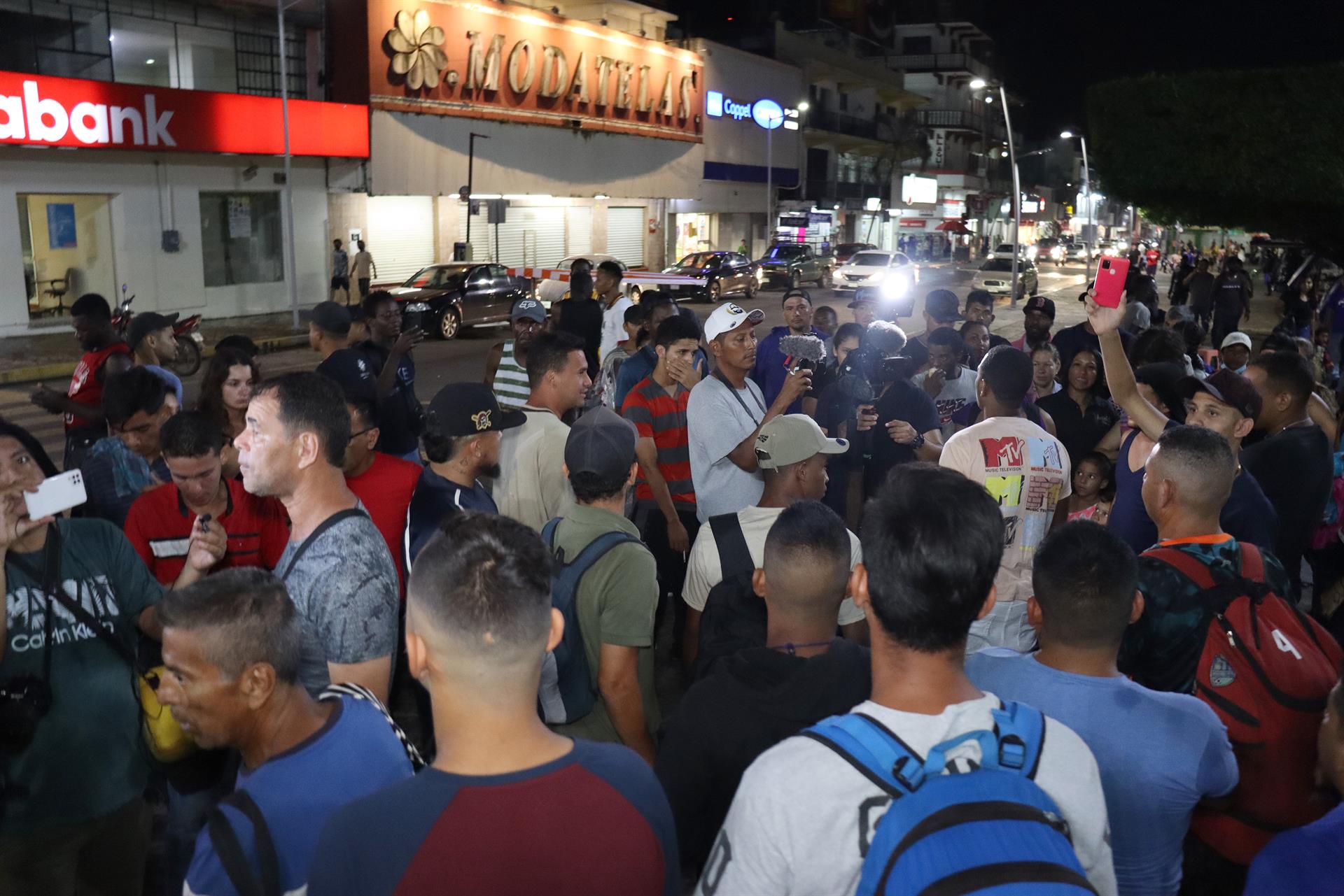 Migrantes permanecen en la calle miemtras membros de la Guardia Nacional y del Instituto Nacional de Migración (INM) realizan un operativo