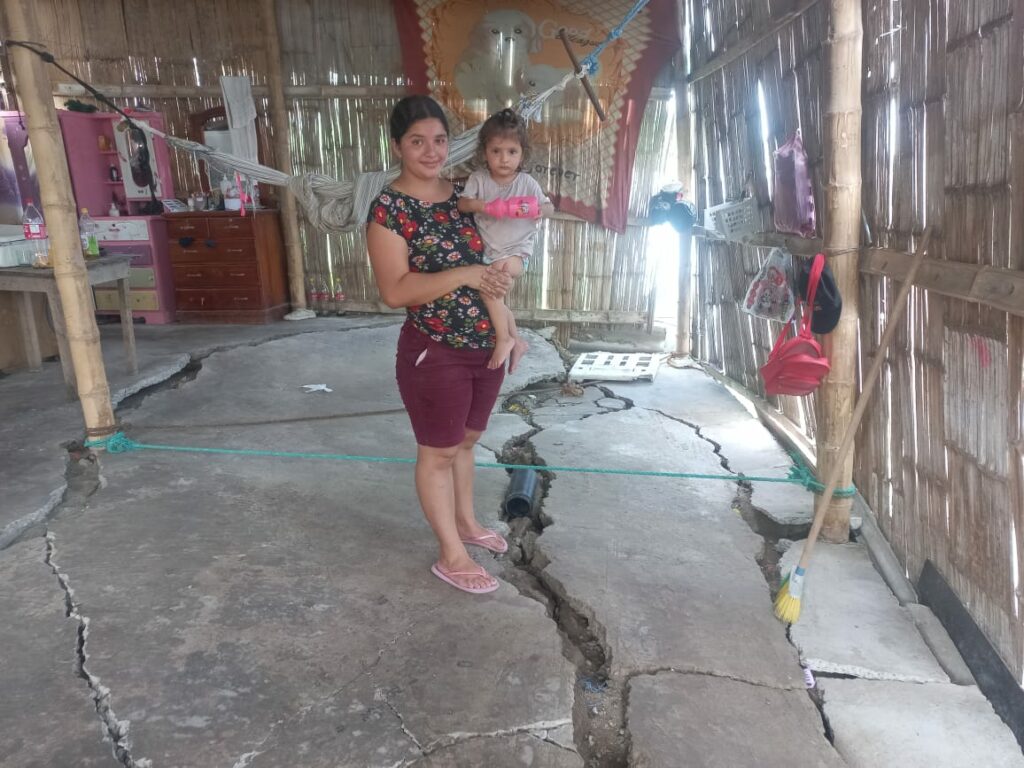 Gema Zambrano carga a su hija menor en medio de su casa, donde el cemento del piso se ha partido por el hundimiento de tierra.