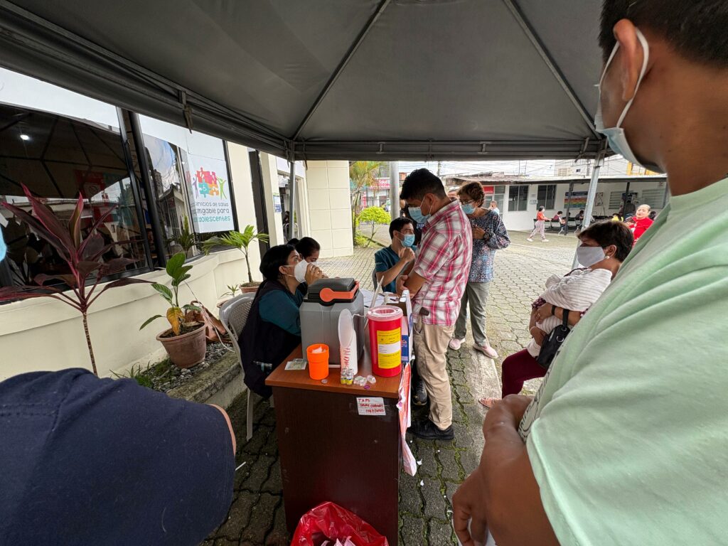 Ciudadanos esperan su turno en la fila por la vacunación contra la tosferina en el subcentro Los Rosales, en Santo Domingo, en medio de medidas de prevención.