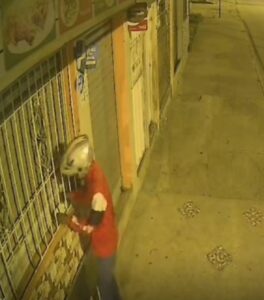 Uno de los detenidos dejando un panfleto amenazante en un local comercial.