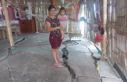 Gema Zambrano carga a su hija menor en medio de su casa, donde el cemento del piso se ha partido por el hundimiento de tierra.