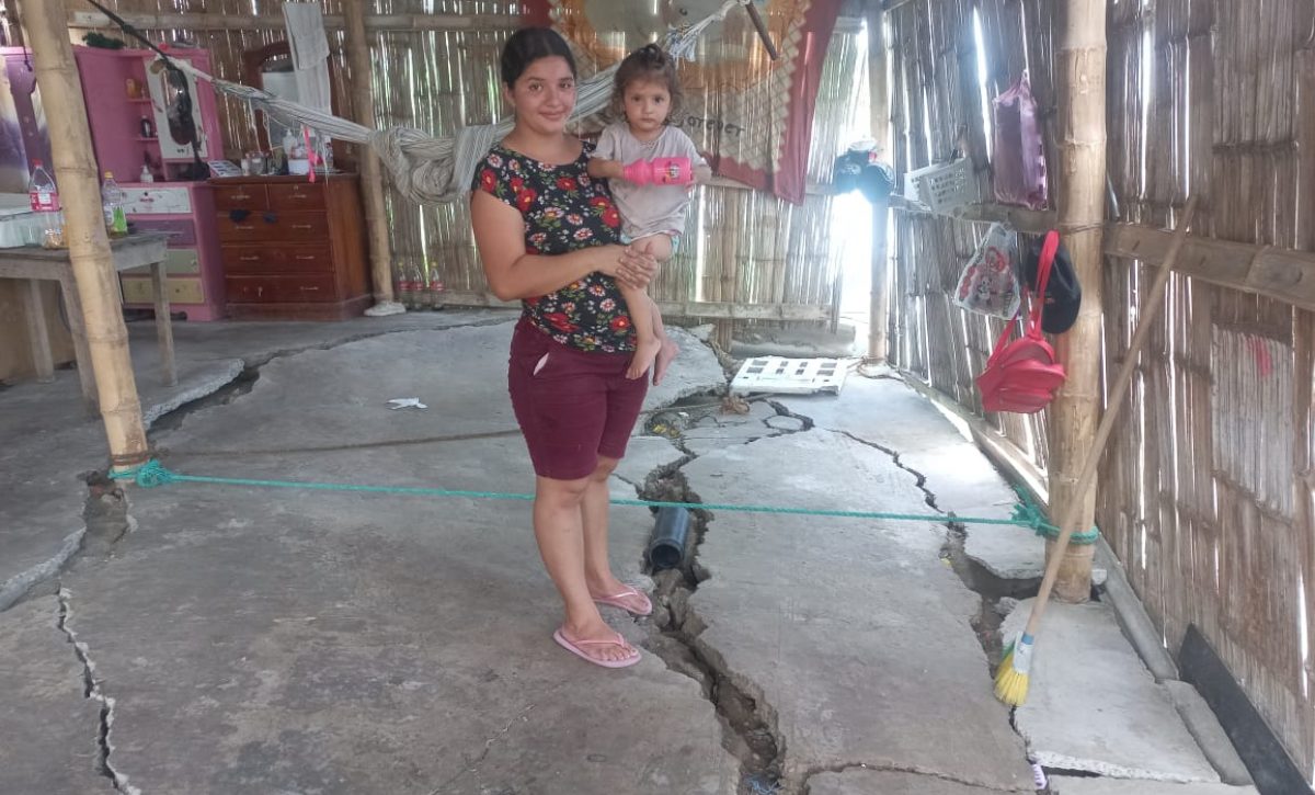 Gema Zambrano carga a su hija menor en medio de su casa, donde el cemento del piso se ha partido por el hundimiento de tierra.