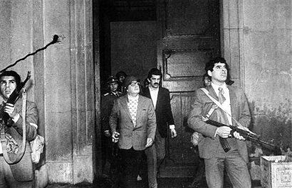 El presidente Salvador Allende, con un casco, junto a guardaespaldas mientras las fuerzas de Augusto Pinochet continuaban su asedio armado contra el palacio presidencial. (Reuters).