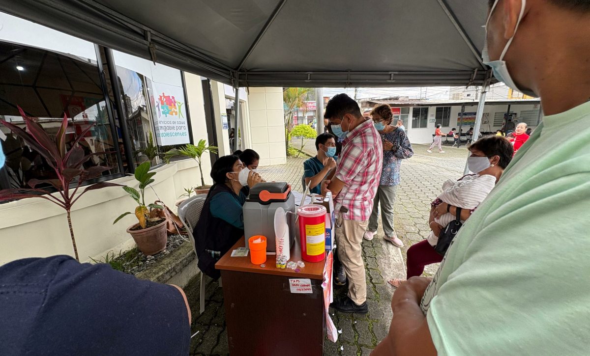 Ciudadanos esperan su turno en la fila por la vacunación contra la tosferina en el subcentro Los Rosales, en Santo Domingo, en medio de medidas de prevención.