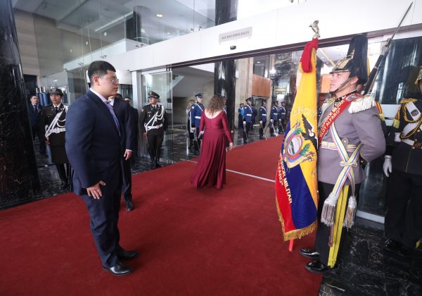 Dominique Serrano asambleísta de Ecuador saludando la Bandera
