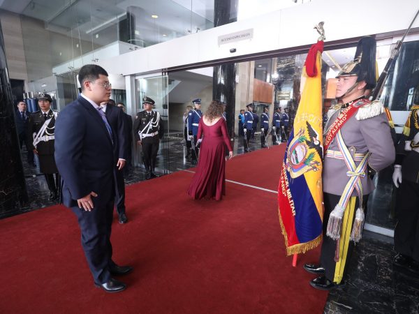 Dominique Serrano asambleísta de Ecuador saludando la Bandera