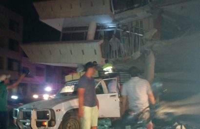 Policías y voluntarios intentan rescatar a una familia de una casa destruida en Portoviejo, la noche del 16 de abril de 2016.