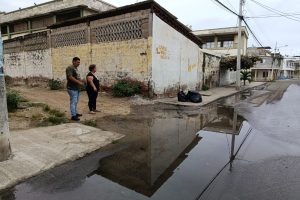Rita González junto a otro vecino mostrando una de las filtraciones de agua en la esquina de la ex escuela Abraham Linconl donde se evidencian dos fugas de agua potable en la acera.