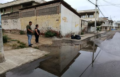 Rita González junto a otro vecino mostrando una de las filtraciones de agua en la esquina de la ex escuela Abraham Linconl donde se evidencian dos fugas de agua potable en la acera.