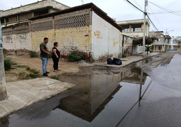 Rita González junto a otro vecino mostrando una de las filtraciones de agua en la esquina de la ex escuela Abraham Linconl donde se evidencian dos fugas de agua potable en la acera.