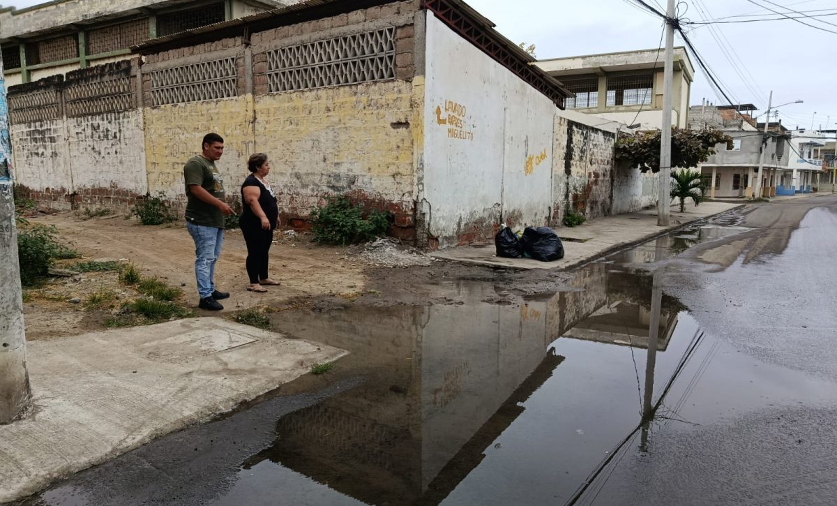 Rita González junto a otro vecino mostrando una de las filtraciones de agua en la esquina de la ex escuela Abraham Linconl donde se evidencian dos fugas de agua potable en la acera.